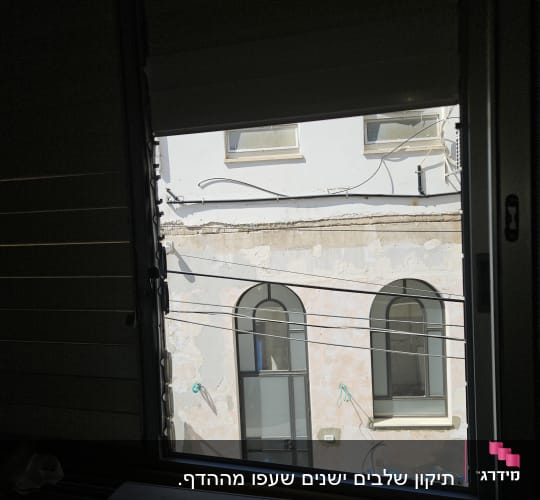 תריסים פתוחים עם נוף של בניין ממול